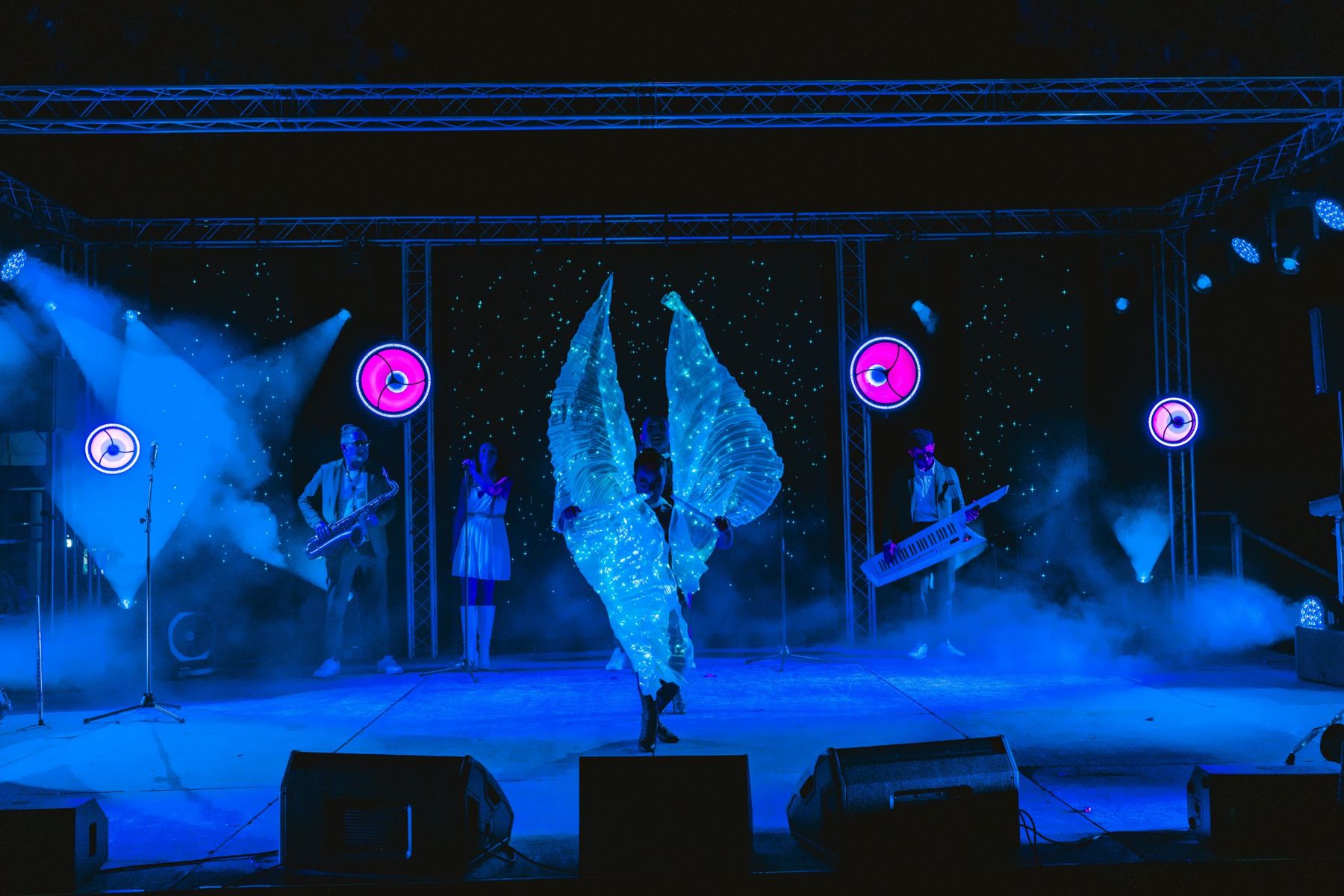 Danseuse aux ailes lumineuses devant le groupe, lumières bleues